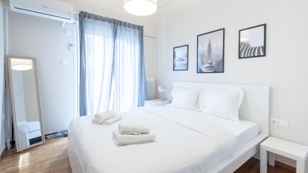 Ein modernes Hotelzimmer mit einem großen Bett, einem Nachttisch, einem Spiegel und zwei gerahmten Bildern an der Wand.