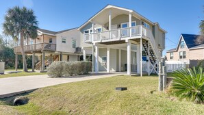 A two-story house with a balcony, a covered porch, and a staircase leading to the upper level. - < 1 Mi to Beach! Poolside Retreat in Galveston (Galveston)
