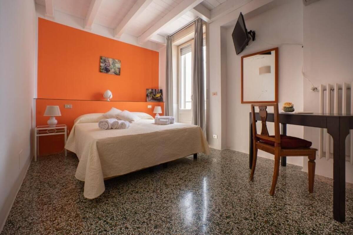 Een hotelkamer met een bed, een bureau, een stoel, een televisie en kunst aan de wanden.