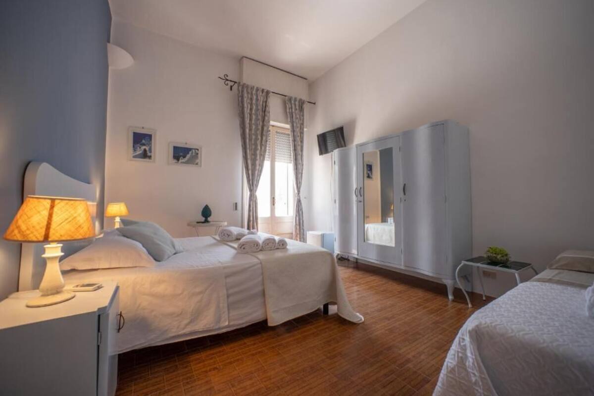 Een hotelkamer met twee bedden, een garderobe, een bureau met lamp en een kleine tafel met een plant.