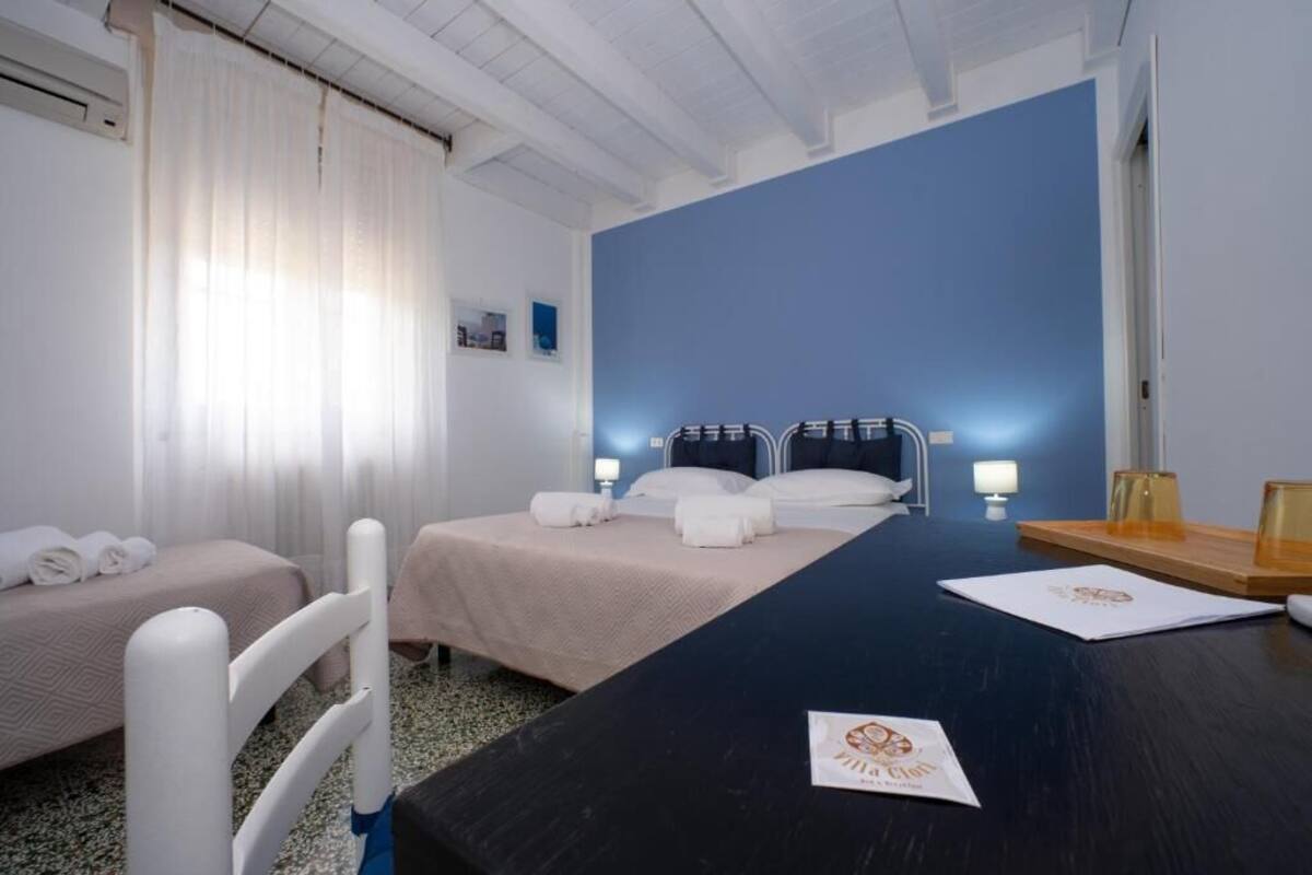 Een hotelkamer met twee bedden, een donker houten tafel en een blauwe accentmuur.