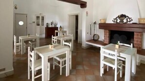 Un comedor amplio con mobiliario blanco y una chimenea de ladrillo.