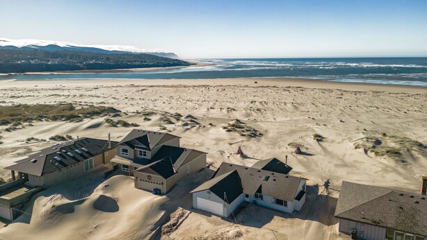 Eine Küstenlandschaft mit Häusern und einem Strand. Die Häuser sind in einer Reihe mit einer Sandauffahrt angeordnet.