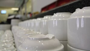 Une rangée de tasses en céramique blanche, dotées de couvercles, probablement dans un magasin ou une cuisine.