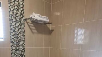 A bathroom with a tiled wall, a white bathtub, and a towel rack.