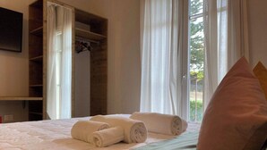 Una habitación de hotel con cama, armario y ventana con cortinas.