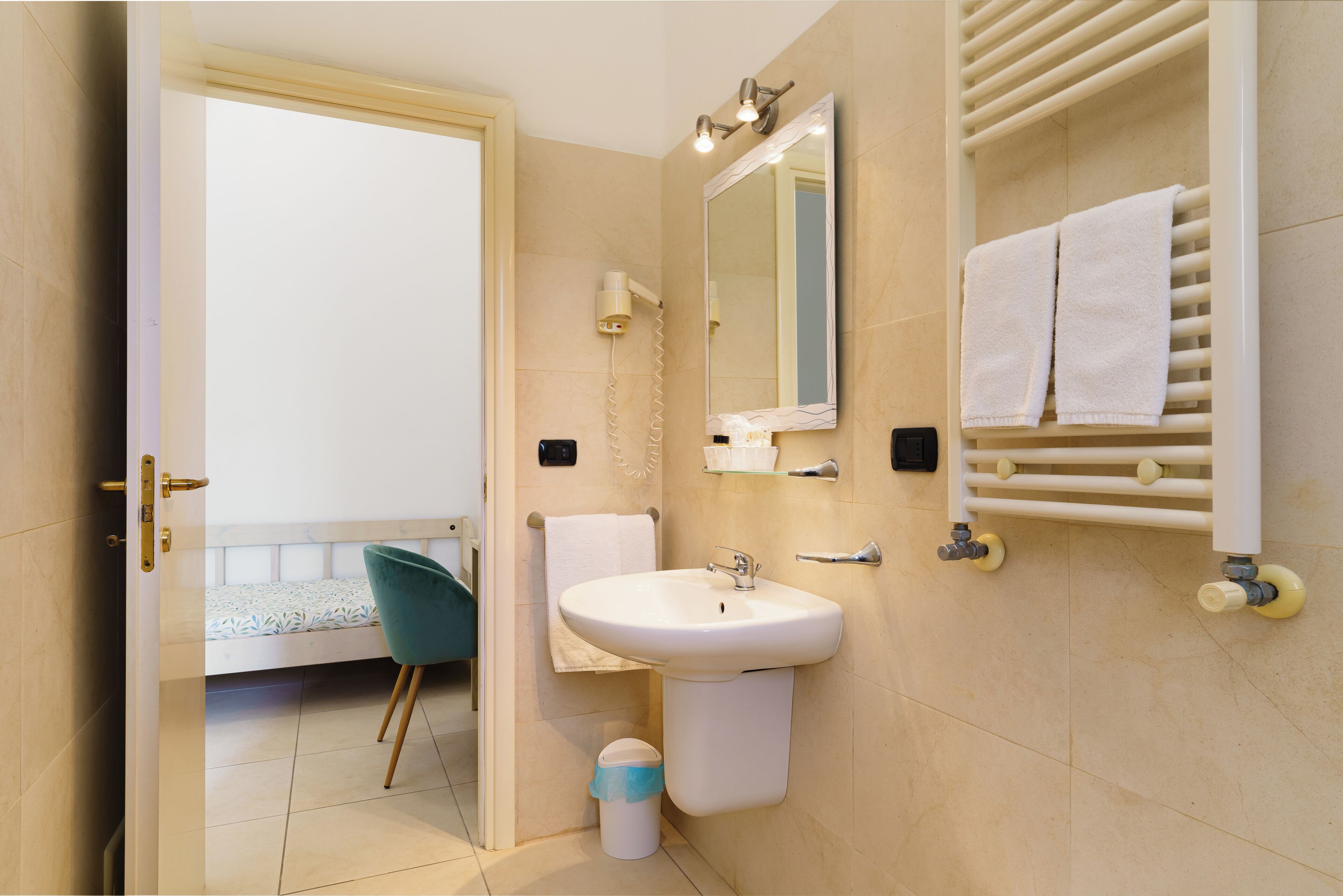 A bathroom with a sink, mirror, towel rack, and a chair.