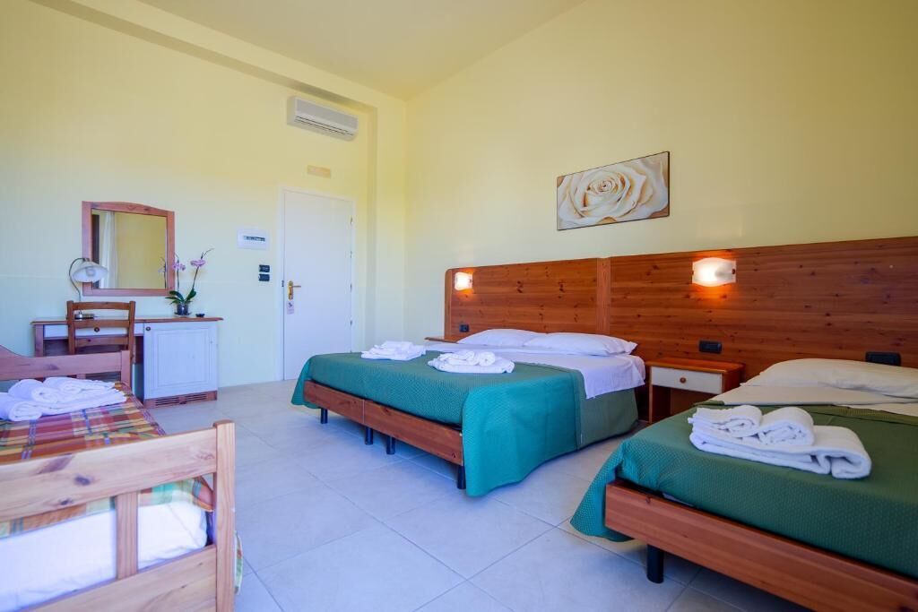 A hotel room with two beds, a wooden headboard, a desk with a mirror, and a small cabinet.