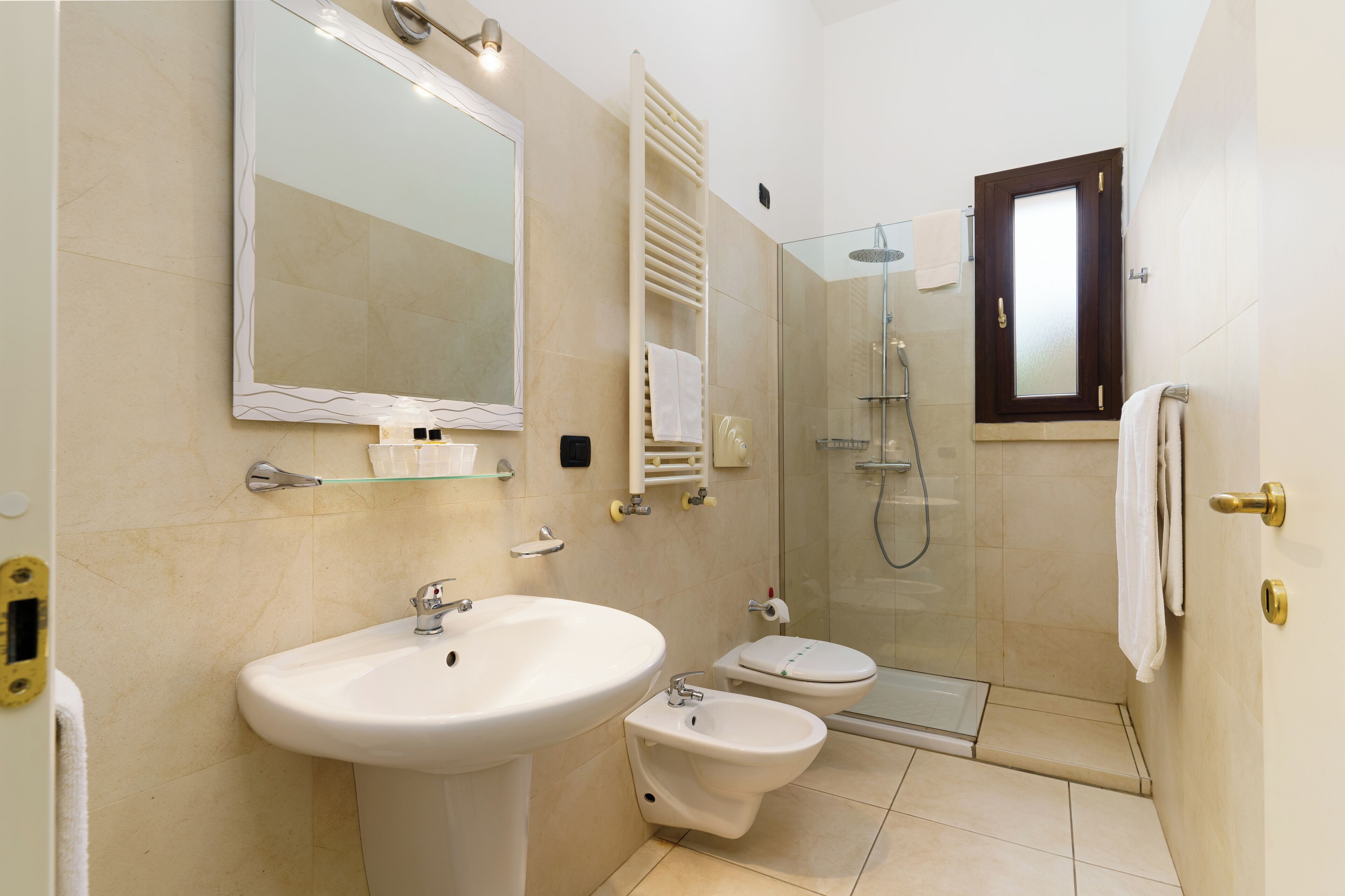 A bathroom with a sink, bidet, toilet, and a glass-enclosed shower.