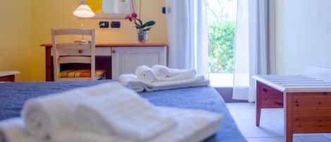 A hotel room with a bed, a desk, a chair, and a small table.