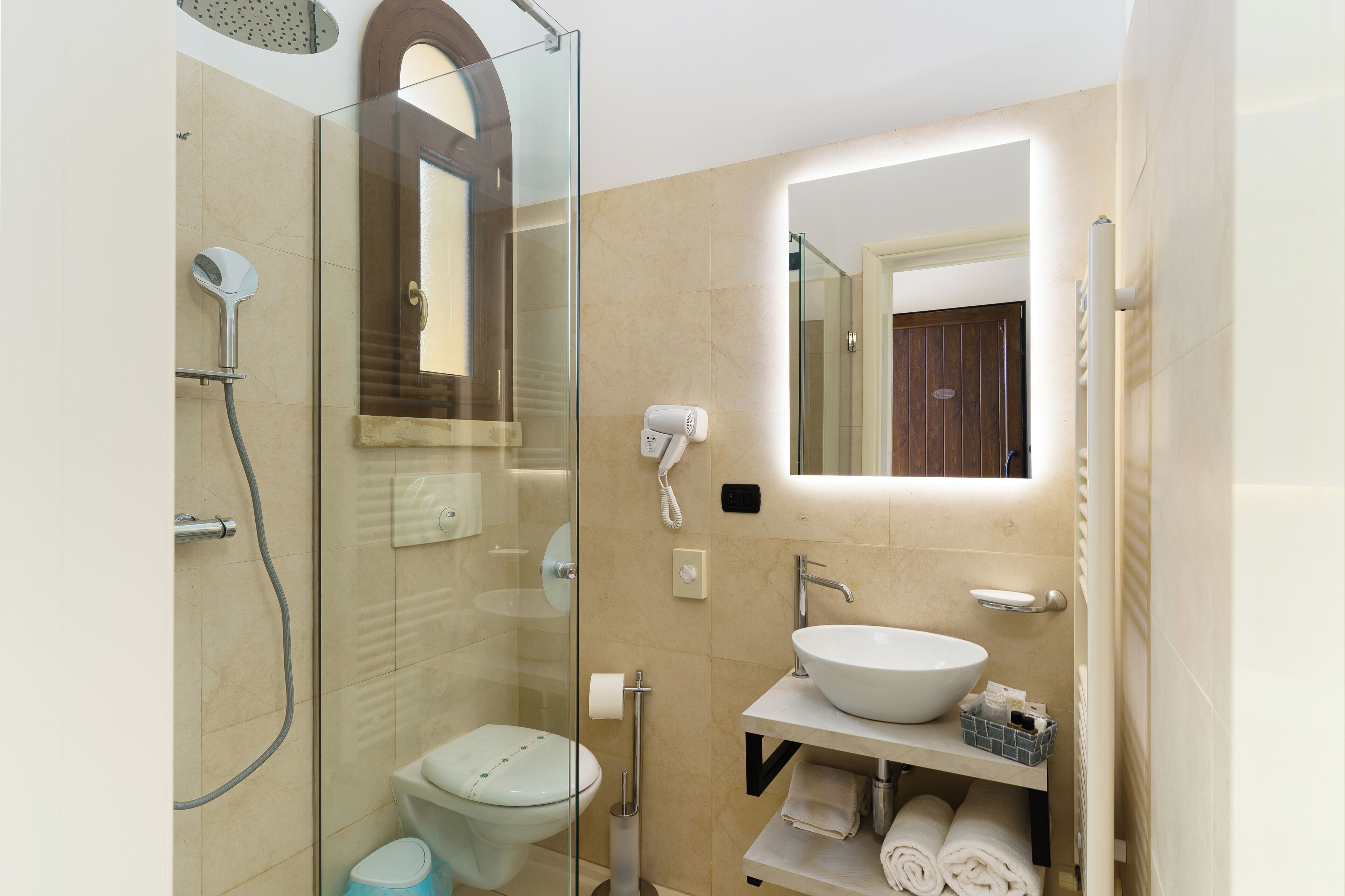 Un baño moderno con ducha de vidrio, lavamanos blanco y un espejo encima.