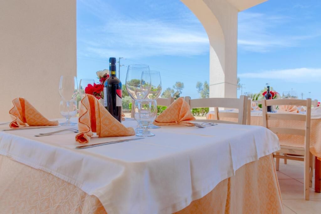 A table set for two with a bottle of wine, glasses, and a vase of flowers.
