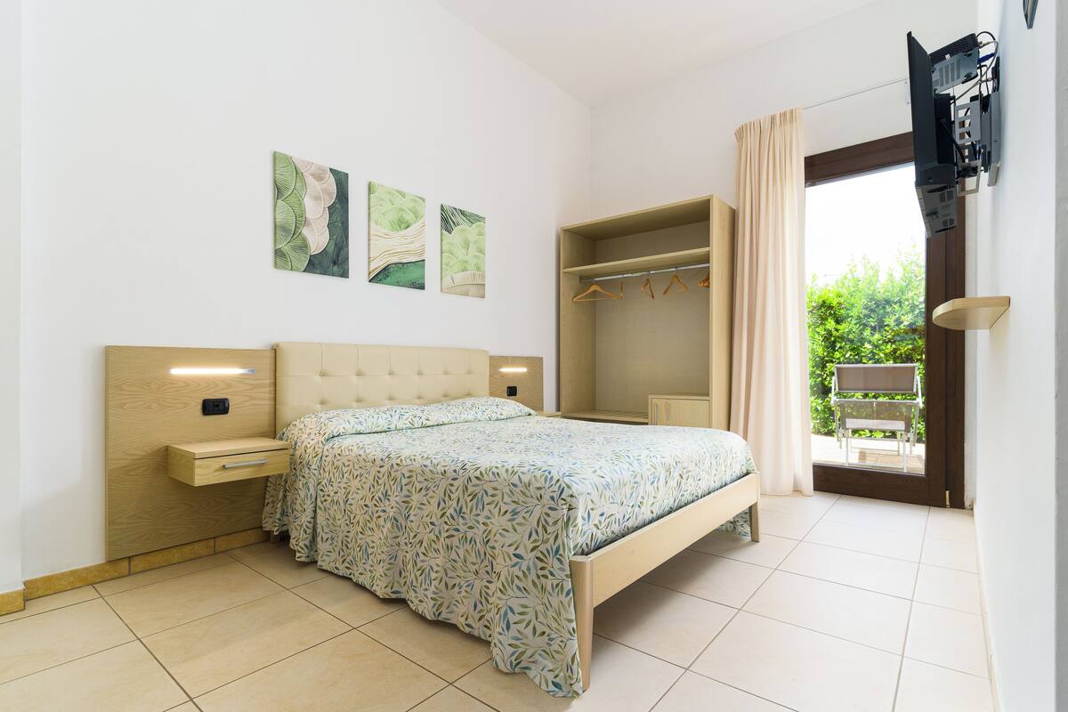 A bedroom with a bed, bedside tables, a wardrobe, and a television mounted on the wall.