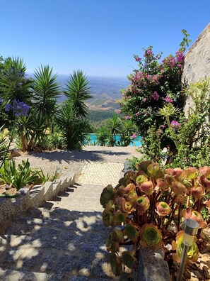 Un sentier de jardin qui mène à une piscine offrant une vue sur le paysage.