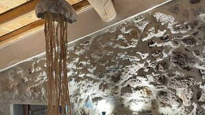 Een rustieke kamer met zichtbare stenen muren, een houten plafond en een blauwgroene kast met licht erboven.
