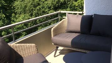 Ein Balkon mit Korbmöbeln, darunter eine Couch und Stühle, sowie ein kleiner Tisch.