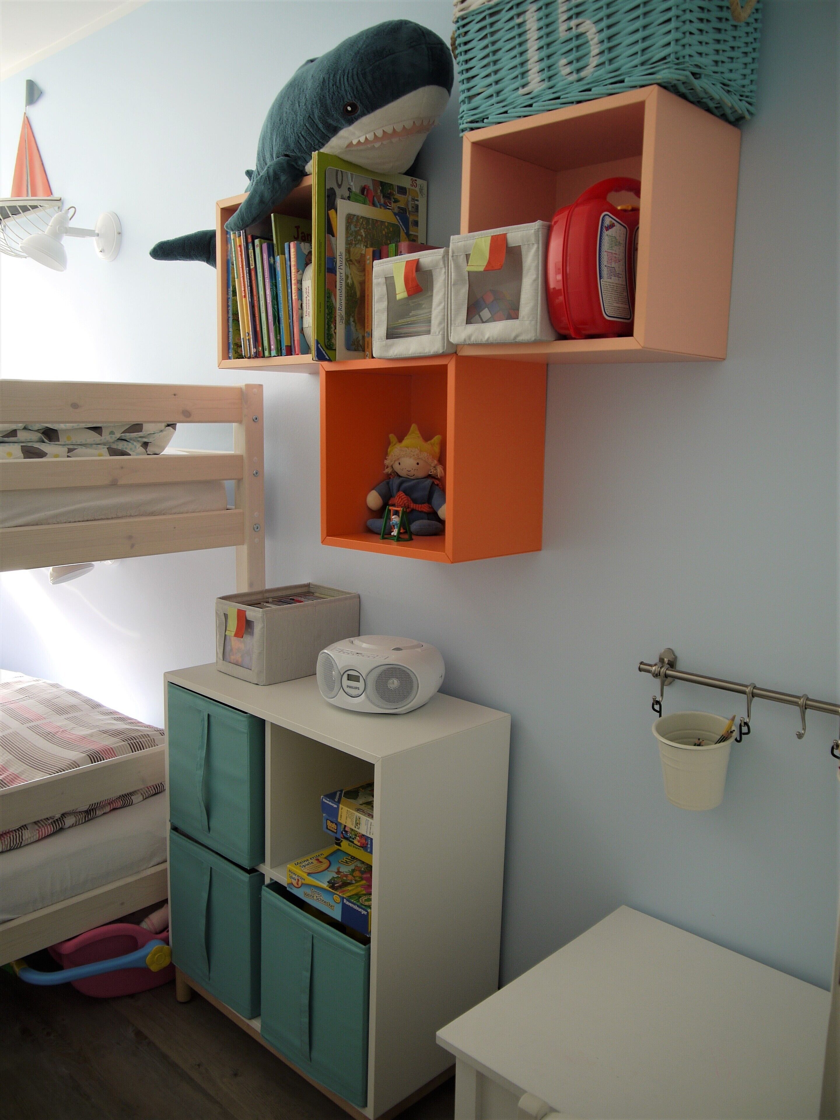 Ein Kinderzimmer mit Etagenbett, Bücherregal, Spielzeughalterung und einem kleinen Tisch mit einem Spielzeugauto.