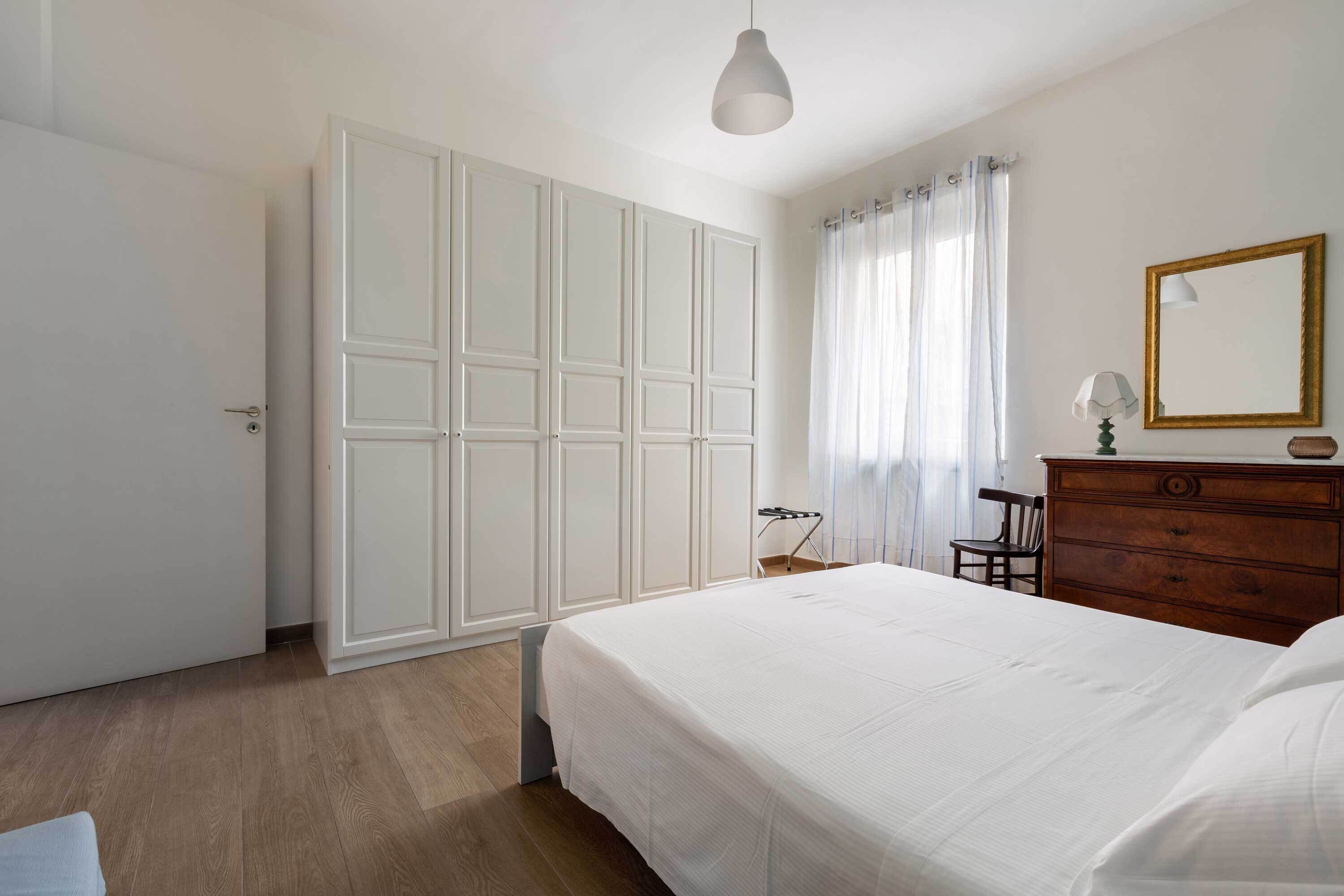 A bedroom with a large bed, a wardrobe, a dresser, and a mirror.