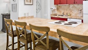 A modern kitchen with a large island, red cabinets, and pendant lighting. - The Olive Shell- condo steps to the beach (St Simons Island)