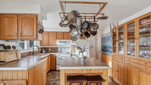 A kitchen with wooden cabinets, a white countertop, and a hanging pot rack.
