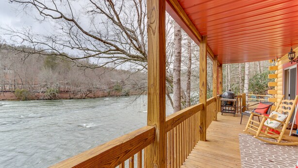 A wooden deck with a view of a river, a rocking chair, and a grill area. - 'Toccoa Waterfront Hideaway:' Hot Tub & Fire Pit! (Mineral Bluff)