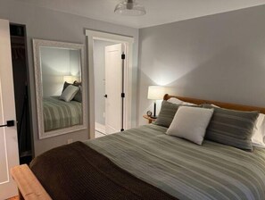 Ein Schlafzimmer mit Bett, Nachttisch, Lampe und Spiegel.