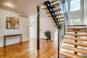 Stunning interior space with a wooden staircase, abstract art, and a potted plant.