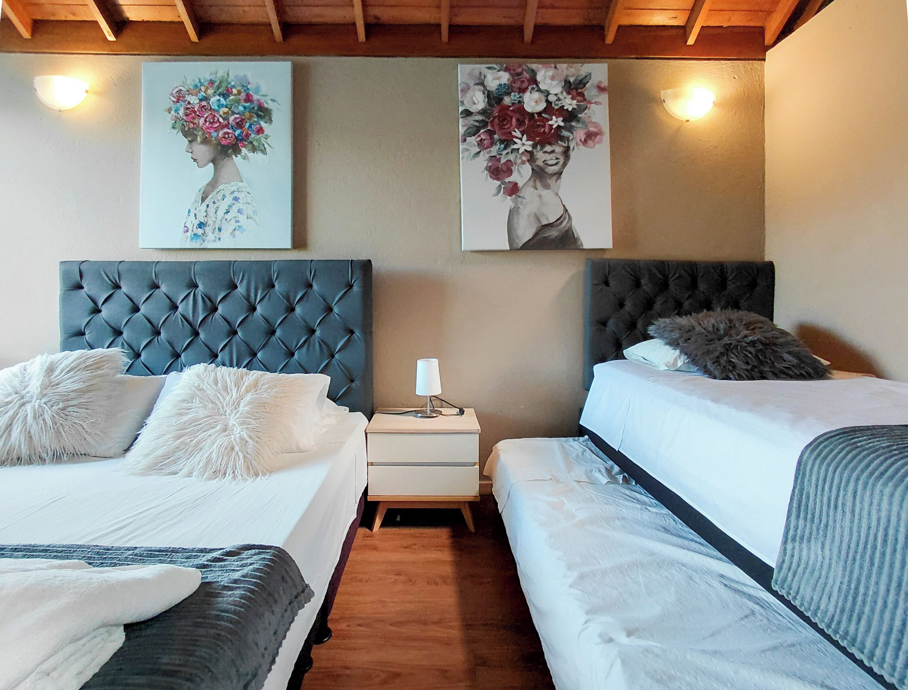 Une chambre d’hôtel avec deux lits, une table de chevet et deux tableaux accrochés au mur.