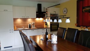 Et moderne køkken med hvide skabe, en træbordplade og et spiseområde med et træbord og stole.
