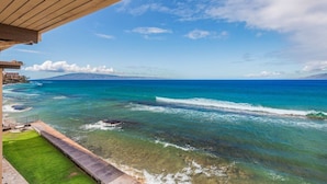A coastal view with clear blue waters, a wooden deck, and a grassy area. - 3BR/2BA OCEANFRONT - Nohonani 403 -  Stunning Views From Every Room, AC & Pool (Lahaina)