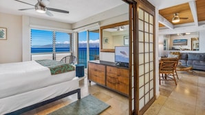 A room with a bed, a desk, and a view of the ocean. - 3BR/2BA OCEANFRONT - Nohonani 403 -  Stunning Views From Every Room, AC & Pool (Lahaina)