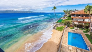 A beachfront property with a swimming pool, a view of the ocean, and a mountain range in the distance. - 3BR/2BA OCEANFRONT - Nohonani 403 -  Stunning Views From Every Room, AC & Pool (Lahaina)