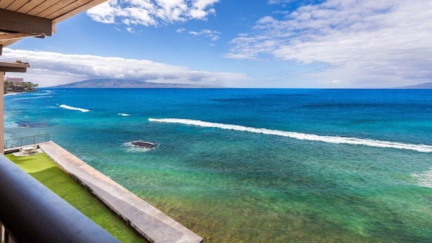 A balcony with a view of the ocean and a distant mountain range. - 3BR/2BA OCEANFRONT - Nohonani 403 -  Stunning Views From Every Room, AC & Pool (Lahaina)