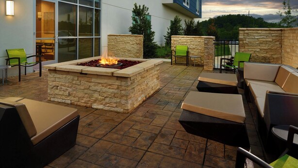 An outdoor patio with stone seating, a fire feature, and a view of the surrounding landscape. - Springhill Suites By Marriott Ellijay (Ellijay)