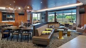 A modern hotel lobby with a seating area, a bar, and large windows offering a view of the outdoors. - Springhill Suites By Marriott Ellijay (Ellijay)
