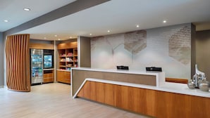 A modern reception area with a wooden reception desk, a refrigerator stocked with beverages, and shelves with various items. - Springhill Suites By Marriott Ellijay (Ellijay)
