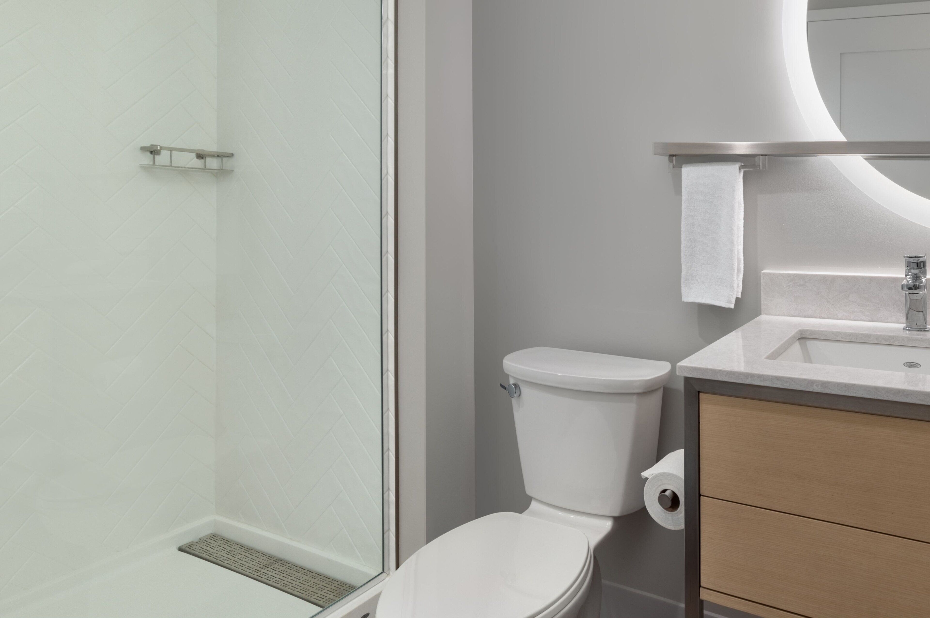 A modern bathroom with a shower, toilet, and sink.