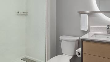 A modern bathroom with a shower, toilet, and sink.