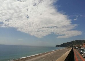 Una carretera costera con una playa a un lado y un paisaje montañoso al otro.