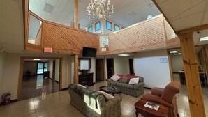 Eine großzügige Lobby mit hoher Decke, einem Kronleuchter und einer Holzboden-Galerie.