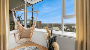 A room with a hanging chair by a large window overlooking a cityscape. - On the Danube, city center, free parking (Bratislava)