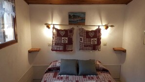 Un dormitorio con una cama, dos almohadas, una estantería y un cuadro.