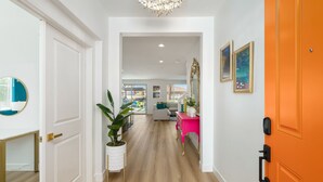 A hallway with a white door, a potted plant, and a bright orange door. - Eclectic Paradise w/Pool & Spa! Close to Festivals (Coachella)