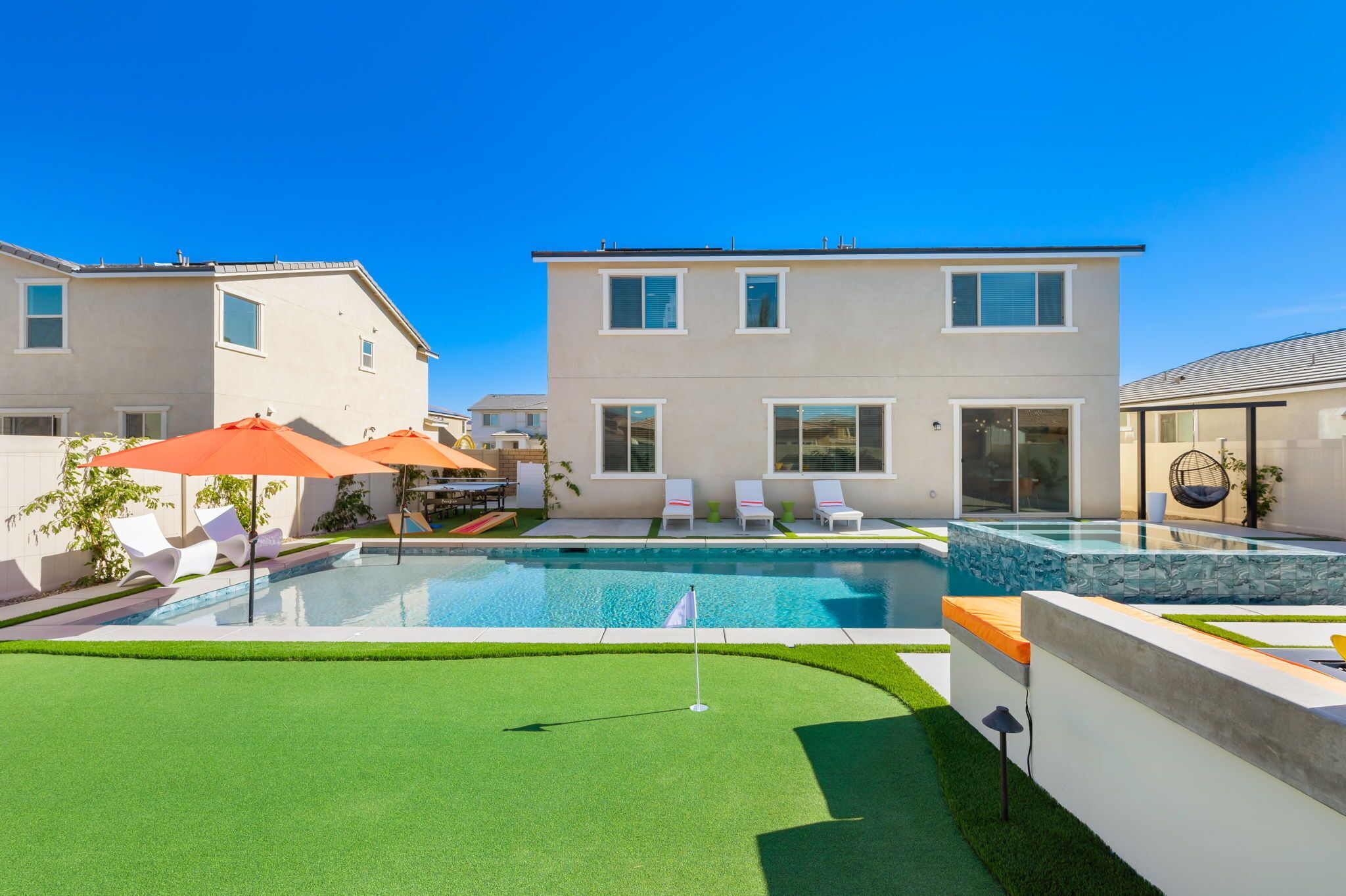 A modern residential building with a swimming pool, outdoor seating, and a well-maintained lawn.