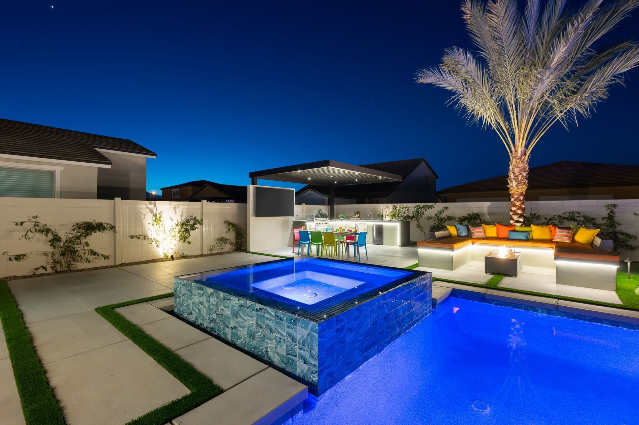 A modern outdoor pool area with a hot tub, seating, and a palm tree.