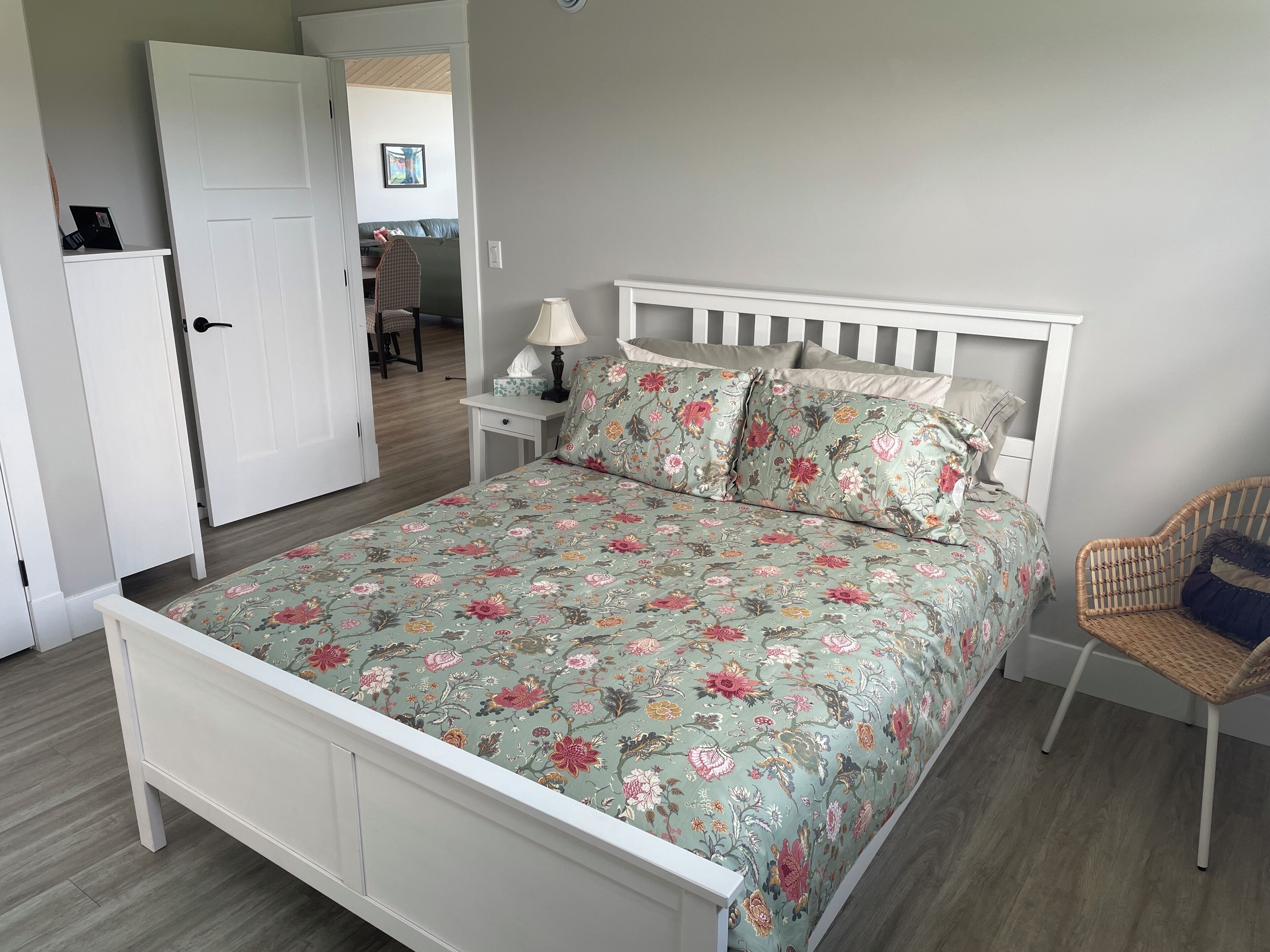 A bedroom with a bed, a chair, a nightstand, and a door.