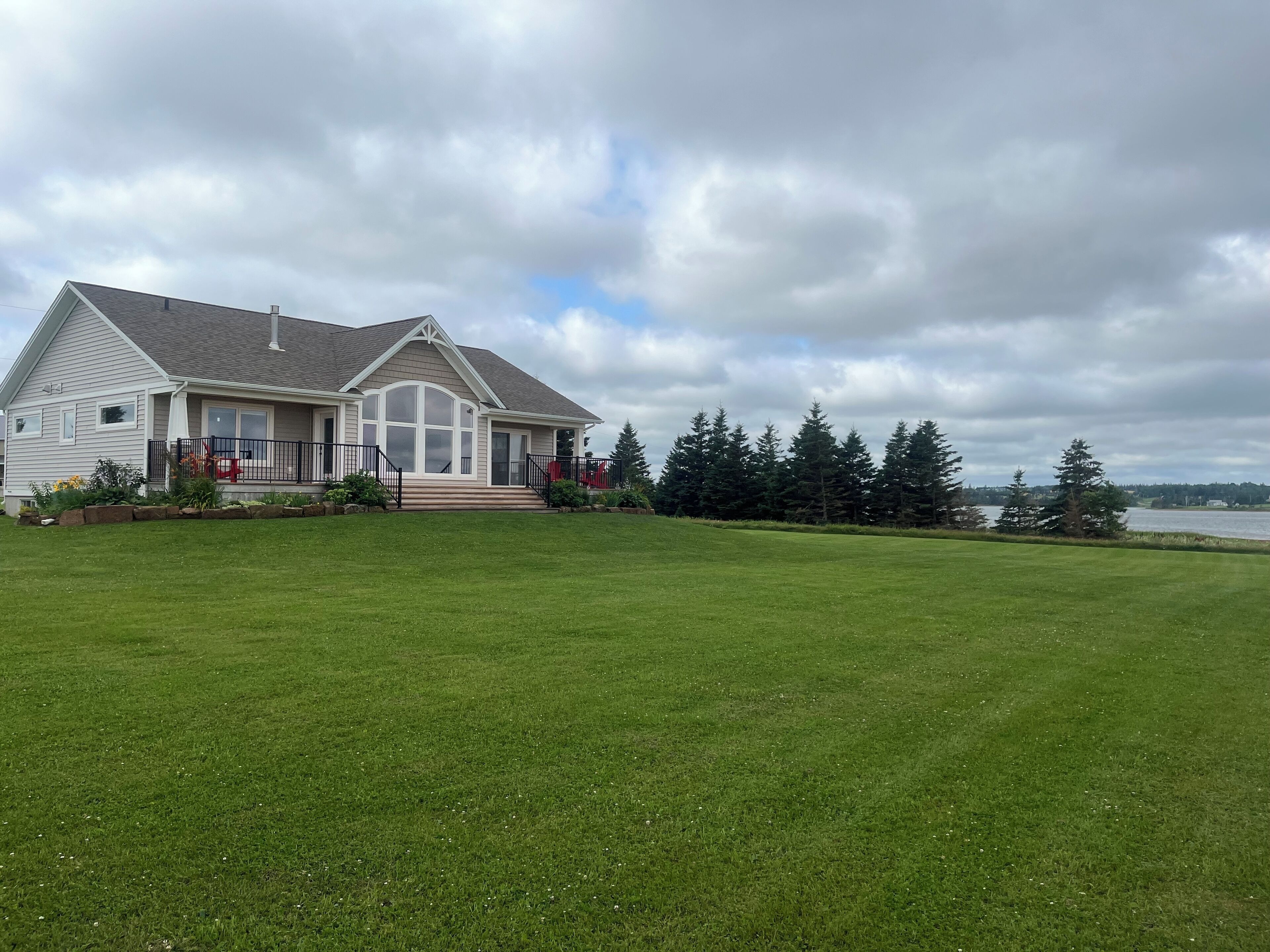 A large house with a well-maintained lawn and a view of a lake.