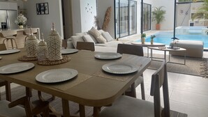 Una sala de estar moderna con comedor, piscina y cocina.