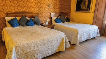 Habitación de hotel con dos camas, una mesita de noche, una lámpara de pared y un cuadro.