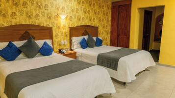 A hotel room with two beds, a nightstand, and a wall lamp.